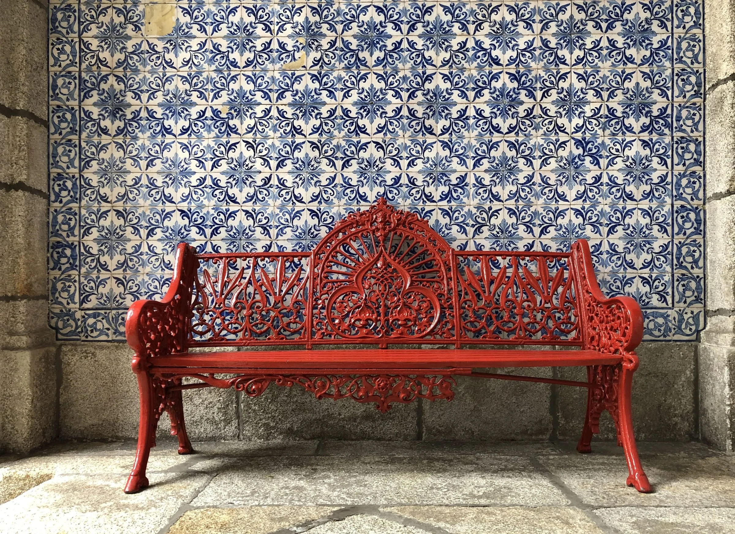 Rode gietijzeren bank voor een wand van blauw-witte azulejos